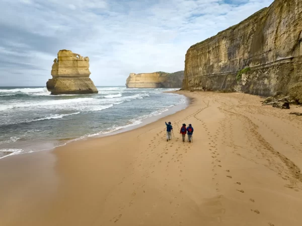 Walkers on Gibson Steps beach beneath limestone cliffs